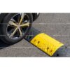 Roue de voiture franchissant un ralentisseur de sécurité noir et jaune de 7 cm sur une chaussée en asphalte.